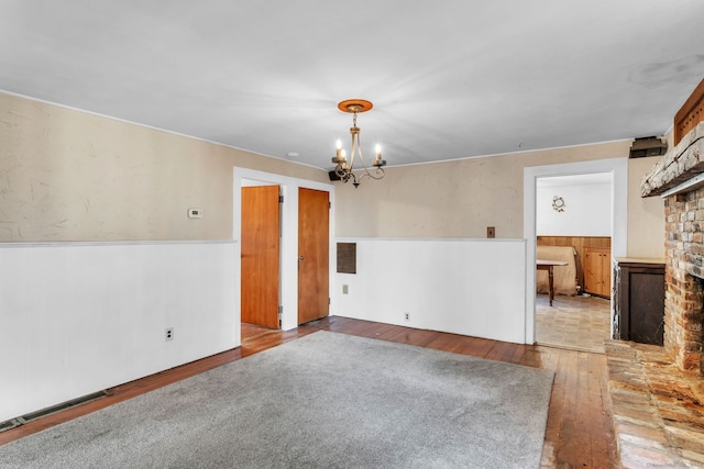 spare room featuring a fireplace, hardwood / wood-style floors, and a chandelier