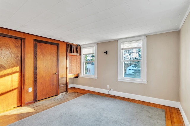 unfurnished bedroom featuring wooden walls and light hardwood / wood-style flooring