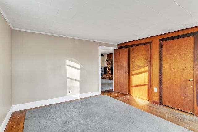 empty room featuring light hardwood / wood-style floors, crown molding, and wood walls