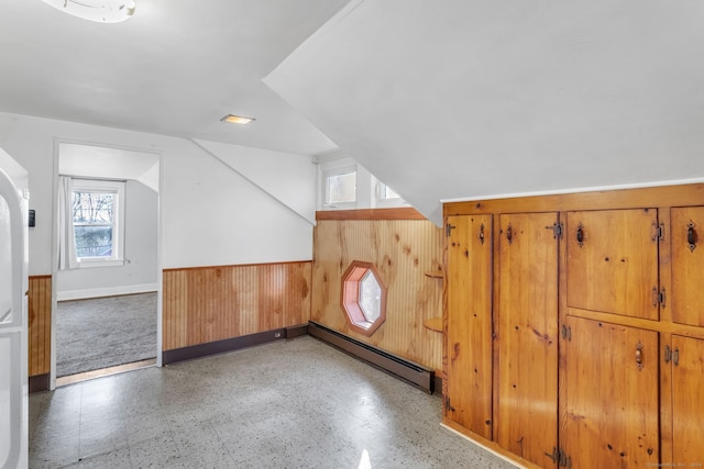 additional living space featuring vaulted ceiling, baseboard heating, and wood walls