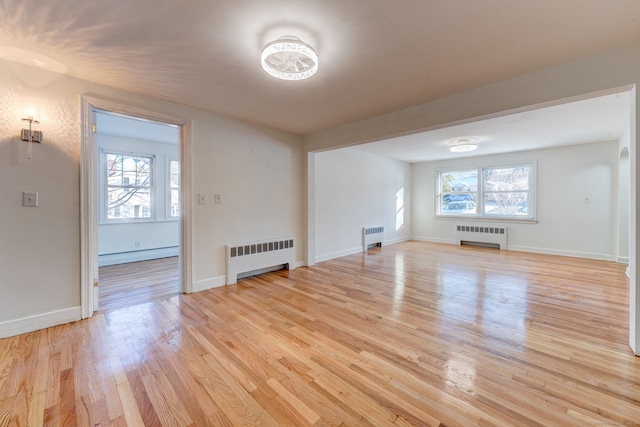 unfurnished living room featuring radiator heating unit, a baseboard radiator, and a healthy amount of sunlight