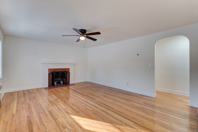 unfurnished living room with a brick fireplace, ceiling fan, and light hardwood / wood-style flooring