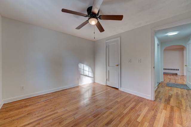 spare room featuring radiator heating unit, light hardwood / wood-style flooring, and ceiling fan