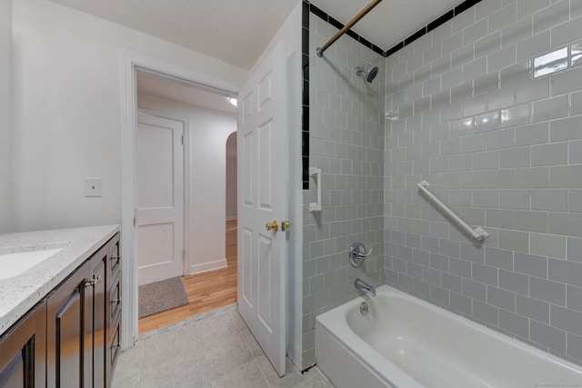 bathroom featuring wood-type flooring, vanity, and tiled shower / bath