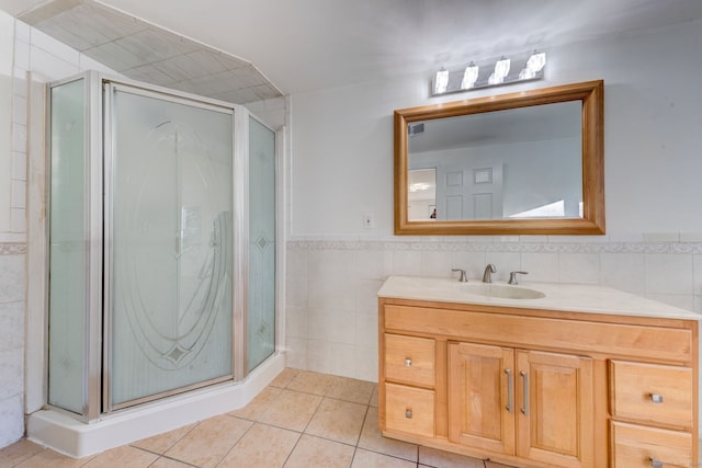 bathroom featuring tile patterned flooring, vanity, tile walls, and a shower with shower door