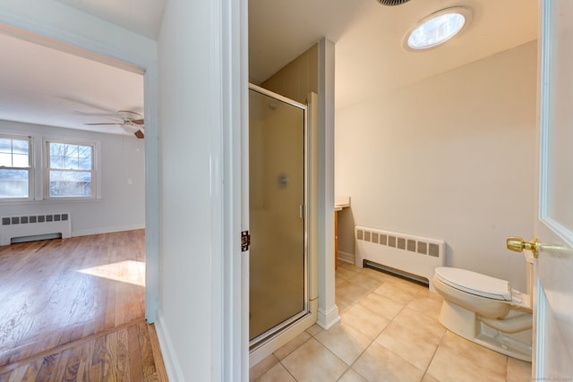 bathroom featuring ceiling fan, wood-type flooring, walk in shower, and radiator