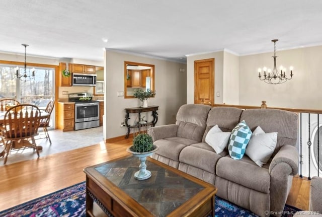 living room featuring ornamental molding, an inviting chandelier, and light hardwood / wood-style floors