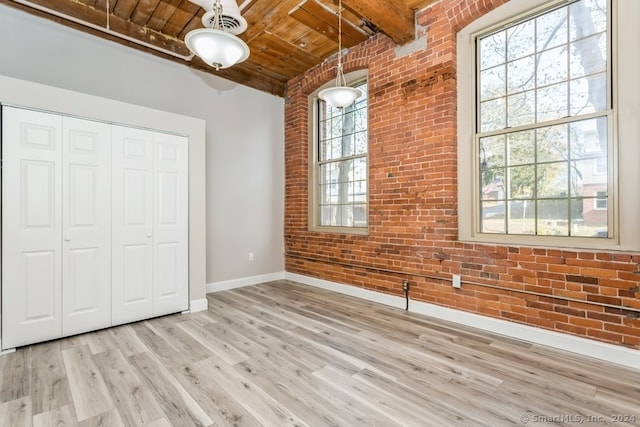 unfurnished bedroom with beamed ceiling, wooden ceiling, brick wall, and light hardwood / wood-style flooring