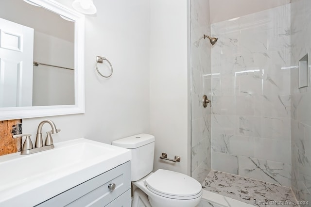 bathroom with a tile shower, vanity, and toilet