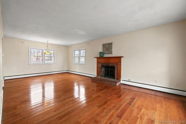 unfurnished living room with wood-type flooring, a baseboard radiator, and a brick fireplace