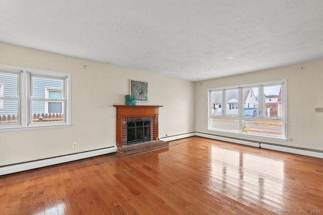 unfurnished living room featuring a fireplace, hardwood / wood-style flooring, and a baseboard radiator