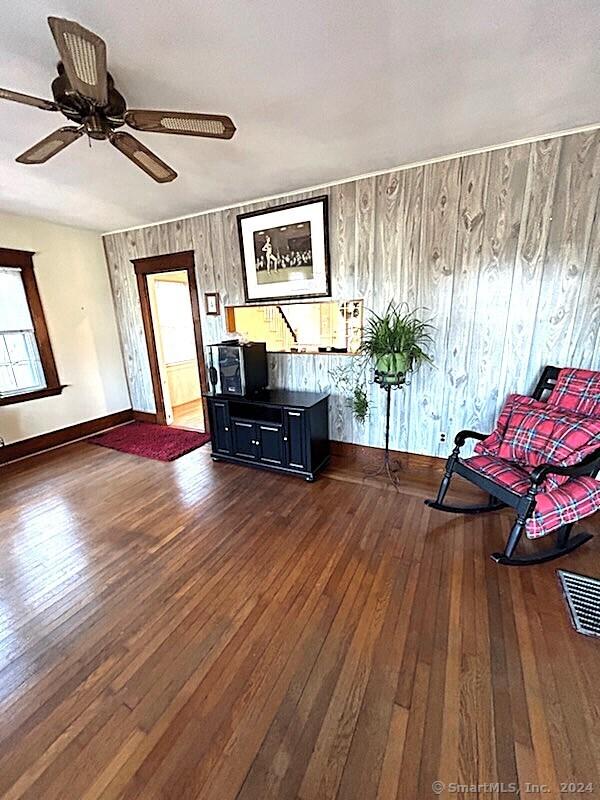 unfurnished room with wooden walls, ceiling fan, and dark wood-type flooring