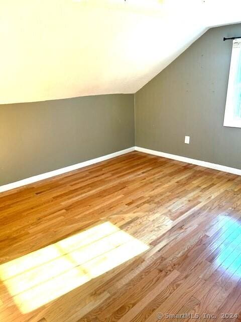 additional living space featuring hardwood / wood-style floors and vaulted ceiling