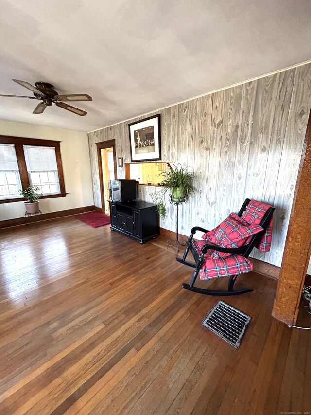 unfurnished room with wooden walls, ceiling fan, and dark wood-type flooring