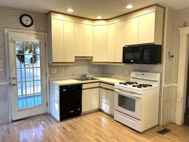 kitchen with sink, black appliances, and light hardwood / wood-style floors