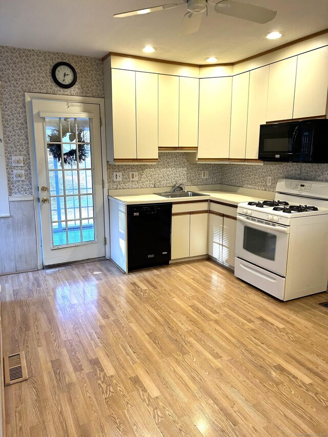 kitchen with sink, light wood-type flooring, white cabinets, and black appliances