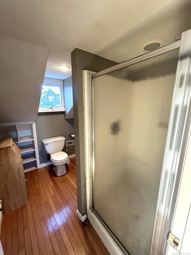 bathroom featuring hardwood / wood-style floors, toilet, and a shower with shower door