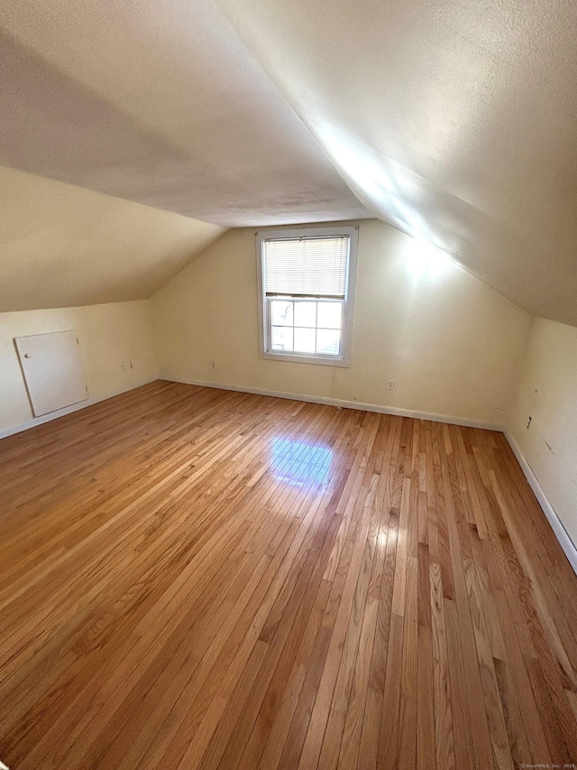 additional living space with lofted ceiling, a textured ceiling, and light hardwood / wood-style flooring