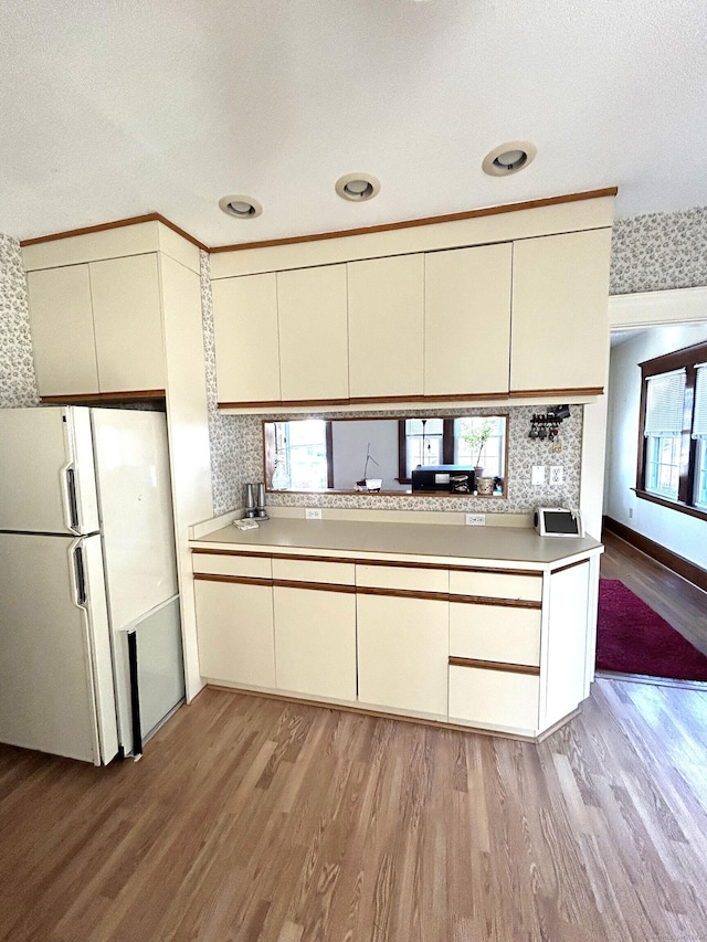 kitchen featuring a wealth of natural light, cream cabinets, light hardwood / wood-style floors, and white refrigerator