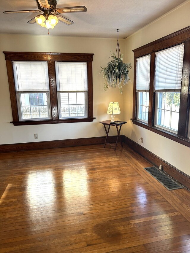 empty room featuring a wealth of natural light, dark hardwood / wood-style flooring, and ceiling fan