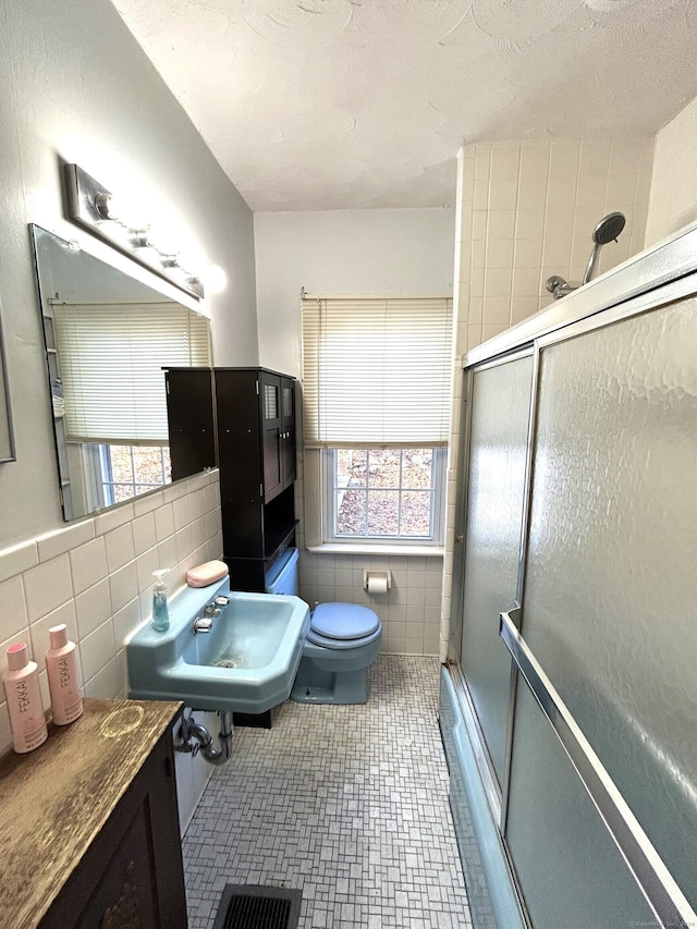 bathroom with sink, tile walls, and toilet