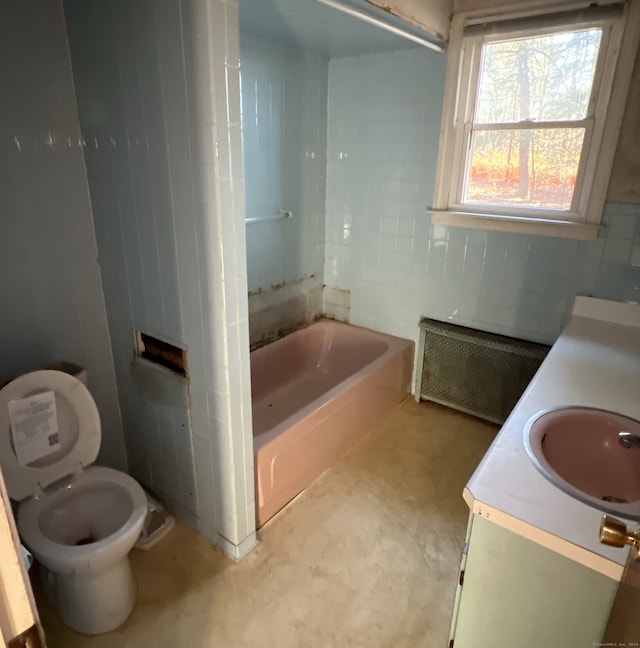 bathroom with vanity, toilet, radiator, and tile walls