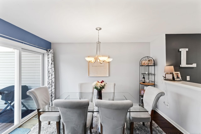 dining space with hardwood / wood-style floors and a notable chandelier