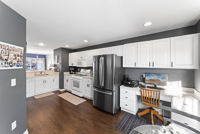 kitchen with white appliances, dark wood-type flooring, sink, pendant lighting, and white cabinets