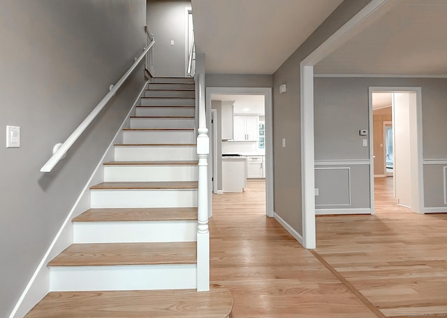 stairs featuring ornamental molding and hardwood / wood-style floors