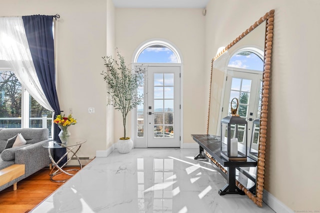 foyer entrance with french doors, hardwood / wood-style flooring, a baseboard radiator, and plenty of natural light