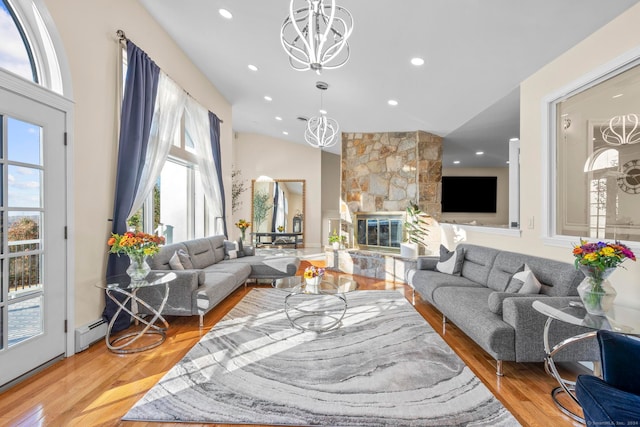 living room featuring a fireplace, hardwood / wood-style floors, vaulted ceiling, and an inviting chandelier