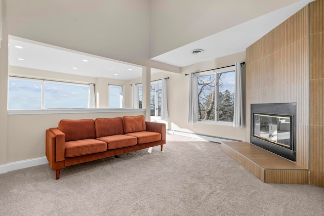 carpeted living room with a fireplace, a healthy amount of sunlight, and a baseboard heating unit