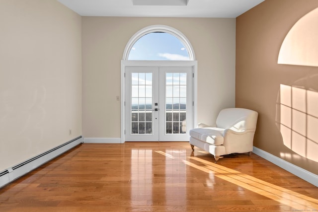 unfurnished room with french doors, a baseboard heating unit, and light hardwood / wood-style flooring