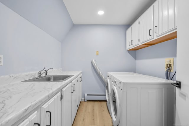 clothes washing area with washer and clothes dryer, cabinets, a baseboard heating unit, sink, and light hardwood / wood-style flooring