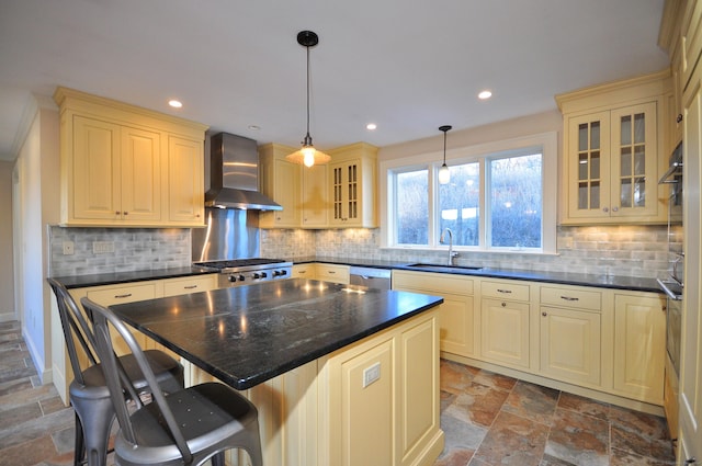 kitchen with stone tile floors, wall chimney exhaust hood, cream cabinetry, and a sink