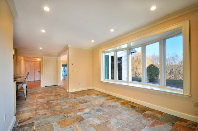 empty room with baseboards, crown molding, stone tile floors, and a wealth of natural light
