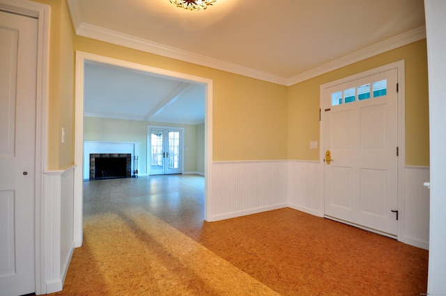 foyer entrance with ornamental molding, a wainscoted wall, and a fireplace