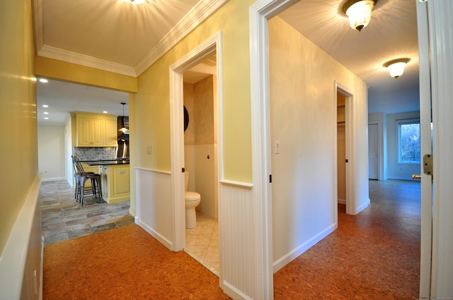 hall with crown molding and a wainscoted wall