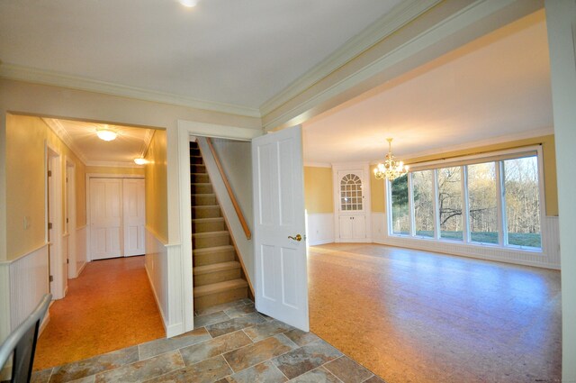 unfurnished room featuring stairway, wainscoting, a chandelier, ornamental molding, and carpet flooring