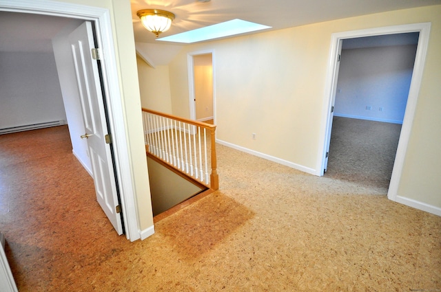 corridor featuring an upstairs landing, a skylight, baseboards, a baseboard radiator, and carpet flooring