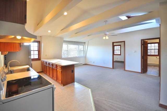 kitchen with white range with electric cooktop, vaulted ceiling with skylight, a sink, brown cabinets, and freestanding refrigerator