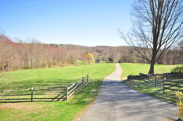 view of community with fence, a rural view, and a yard