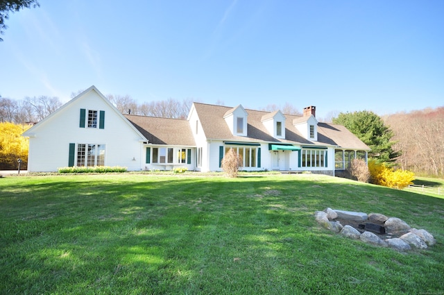 back of house featuring a yard, a shingled roof, and a chimney