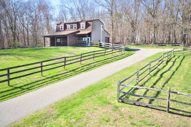 view of property's community featuring a lawn, fence, and aphalt driveway