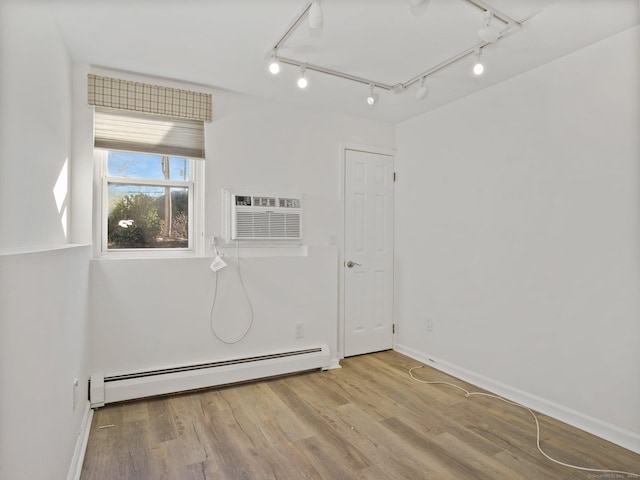 spare room with a baseboard radiator, a wall mounted air conditioner, and light hardwood / wood-style floors