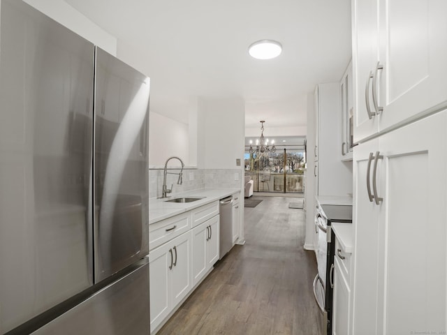 kitchen featuring hardwood / wood-style flooring, pendant lighting, white cabinetry, appliances with stainless steel finishes, and sink