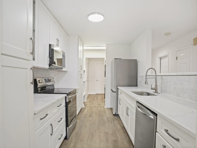 kitchen with stainless steel appliances, backsplash, and white cabinetry