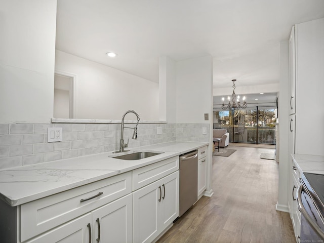 kitchen featuring sink, stainless steel appliances, white cabinetry, an inviting chandelier, and tasteful backsplash