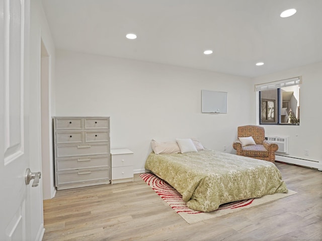 bedroom featuring a baseboard radiator, a wall mounted air conditioner, and light hardwood / wood-style flooring