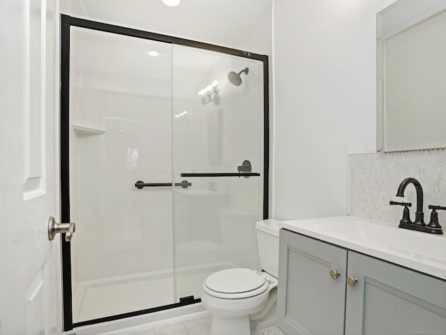 bathroom with a shower with shower door, toilet, tile patterned floors, backsplash, and vanity